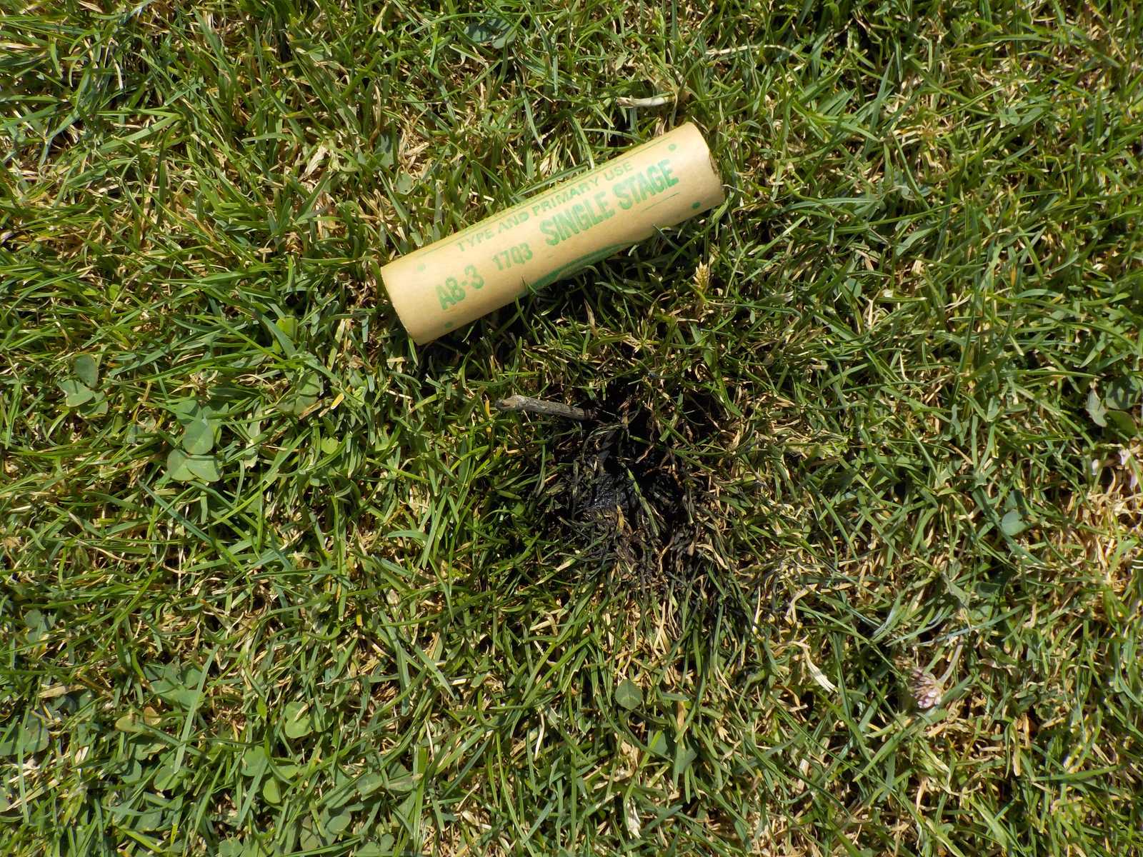 A spent motor casing on grass next to a scorched patch