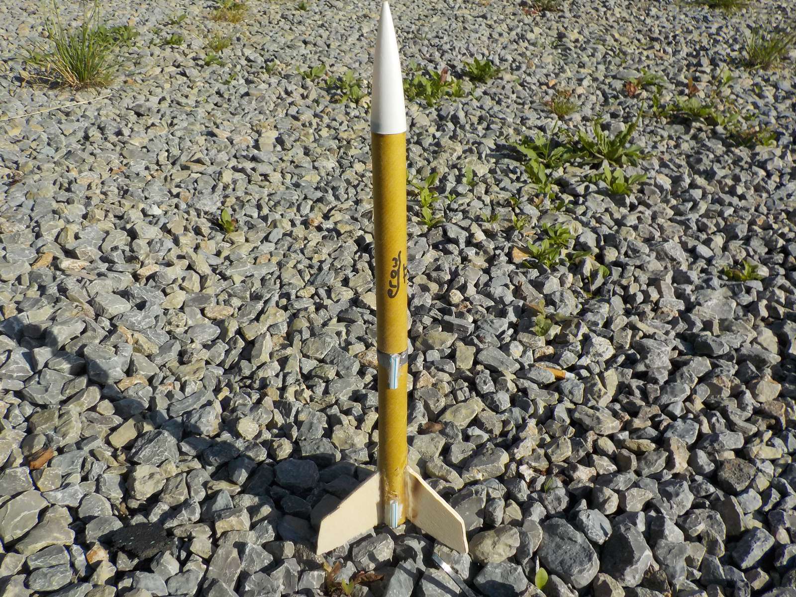 The EA-2 standing on a gravel pad: a yellow tube with a white nose and three fins